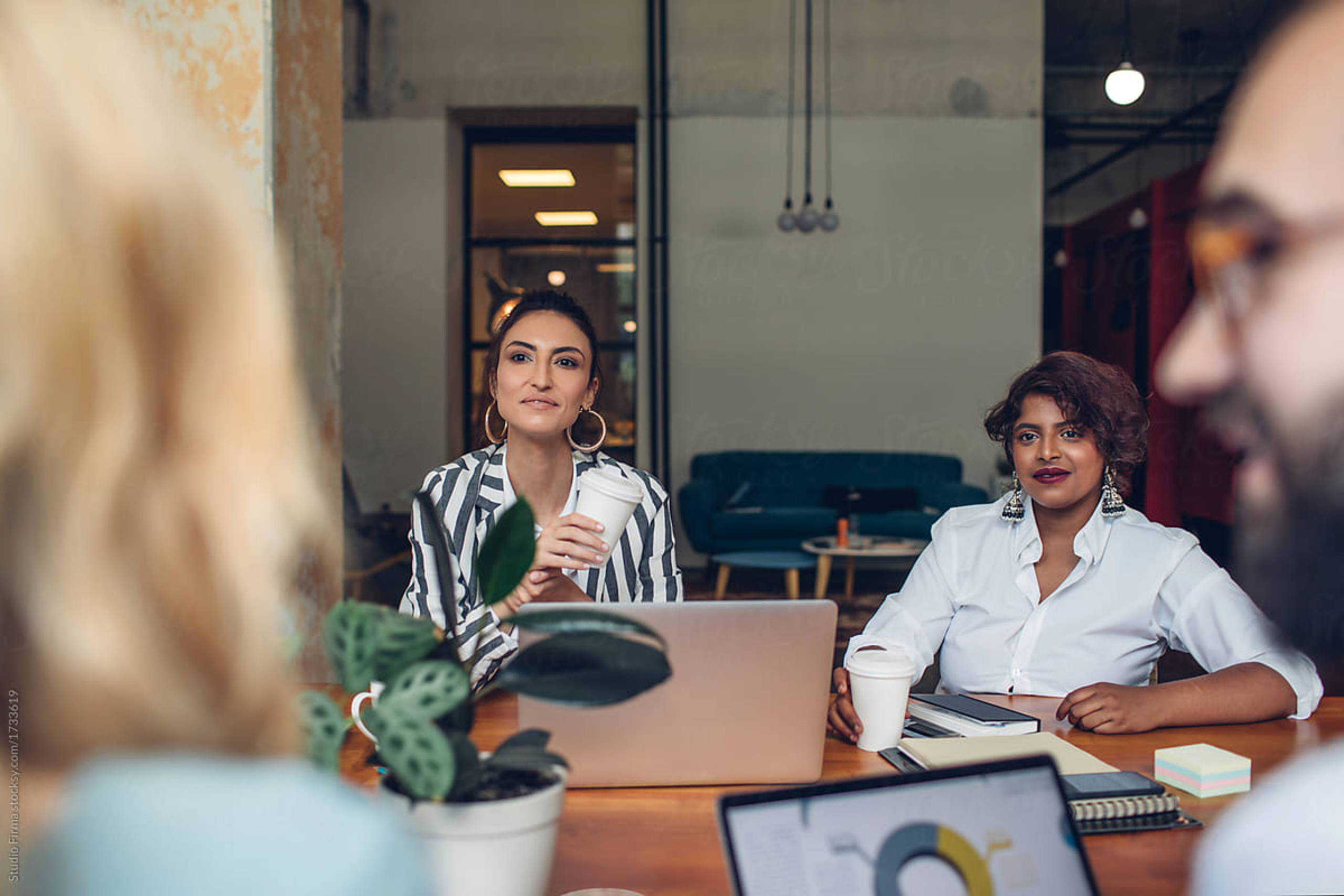 Two women in a meeting with others, discussing Small Business Restructuring (SBR) for addressing excessive tax debt.